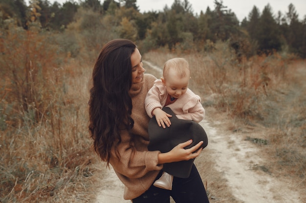 Mère avec petite fille jouant dans un champ d'automne