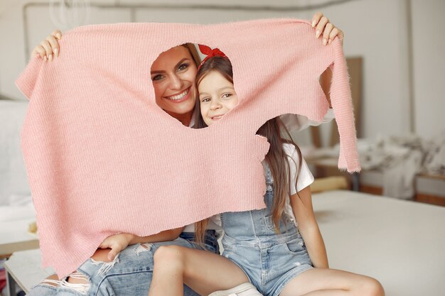 Mère avec petite fille mesure le tissu à coudre