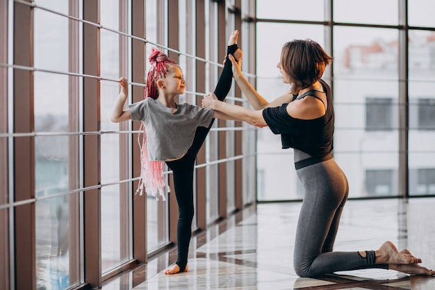 Mère avec petite fille pratiquant le yoga par la fenêtre