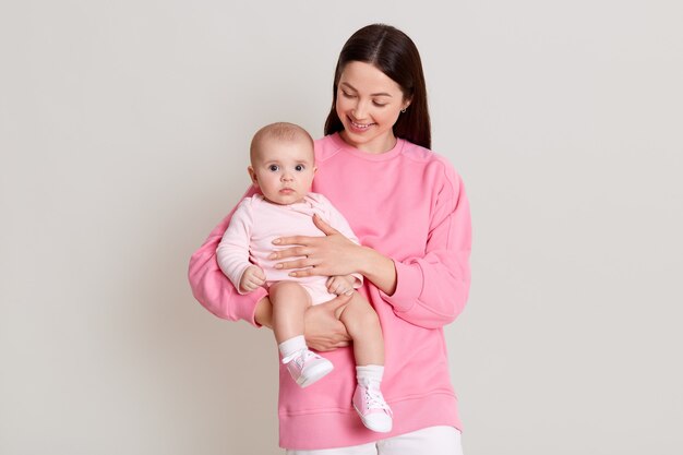 Jolie Jeune Femme Portant Des Leggins Gris Et T Shirt Sans Manches Assis Sur Le Sol Avec Un Enfant Nouveau Ne Une Femme Aux Cheveux Noirs Porte Sa Fille Un Enfant Avec Un Bandeau