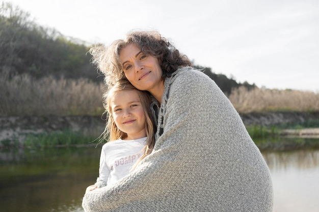 Mère posant avec sa jeune fille à l'extérieur