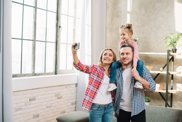 Mère prenant selfie sur téléphone mobile avec son mari et sa fille