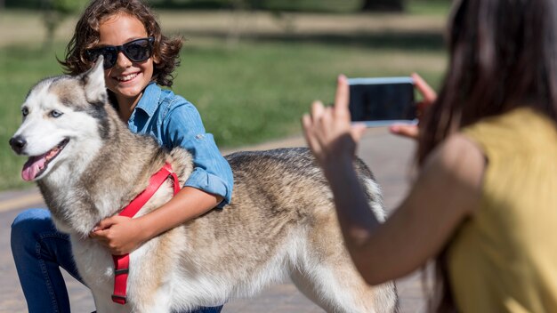 Mère de prendre une photo de fils avec un chien dans le parc