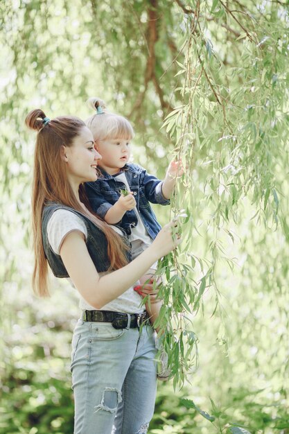 Mère avec sa fille dans les bras en regardant les feuilles d&#39;un arbre