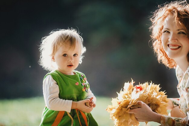 La mère et sa fille gardent des feuilles dans le parc