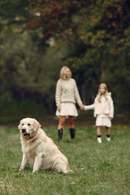 Mère et sa fille jouant avec un chien. Famille dans le parc de l'automne. Concept d'animal de compagnie, d'animal domestique et de mode de vie