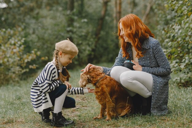 Mère et sa fille jouant avec un chien. Famille dans le parc de l'automne. Concept d'animal familier, animal domestique et mode de vie. Temps de l'automne.