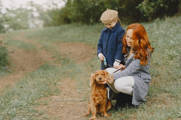 Mère et sa fille jouant avec un chien. Famille dans le parc de l'automne. Concept d'animal familier, animal domestique et mode de vie. Temps de l'automne.