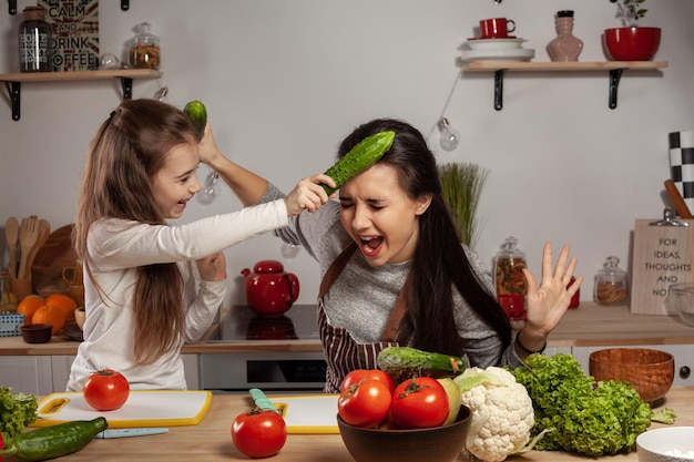 La mère et sa fille préparent une salade de légumes et s'amusent à la cuisine.