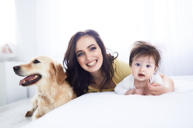 La mère avec sa fille s&#39;allonger sur le lit et le chien assis près du lit