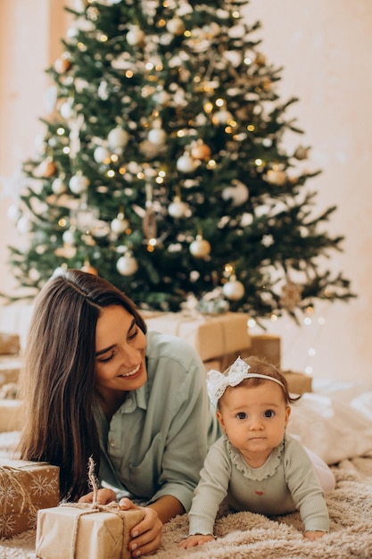 Photo gratuite mère avec sa petite fille avec des coffrets cadeaux près de l'arbre de noël