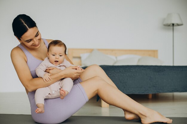 Mère avec sa petite fille pratique le yoga à la maison