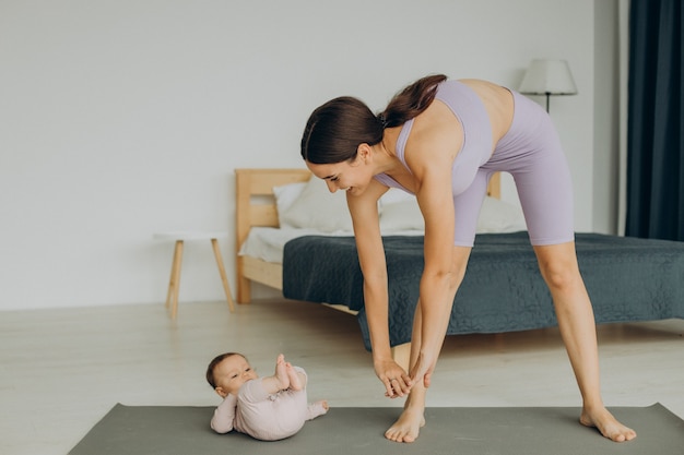 Photo gratuite mère avec sa petite fille pratique le yoga à la maison