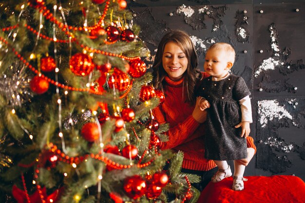 Mère avec sa petite fille près du sapin de Noël