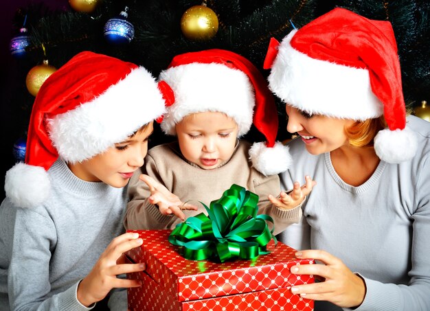 Mère et ses enfants avec cadeau de nouvel an sur les vacances de Noël en attendant le miracle - à l'intérieur