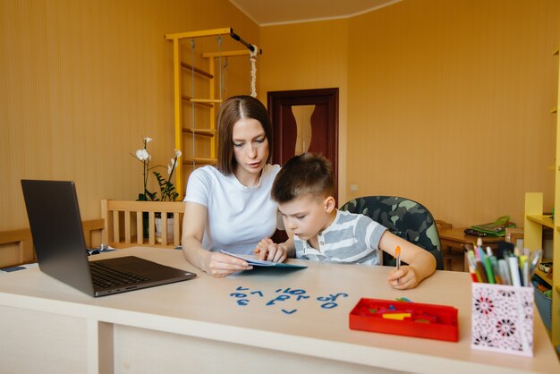 Une mère et son enfant suivent un enseignement à distance à la maison devant l'ordinateur. restez chez vous, entraînez-vous.