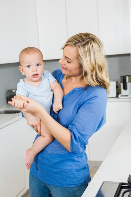 Mère tenant son bébé dans la cuisine