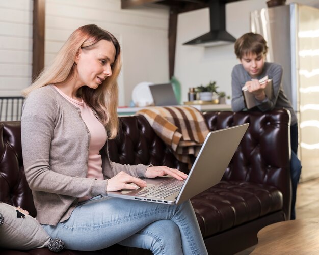 Mère travaillant à distance sur le canapé