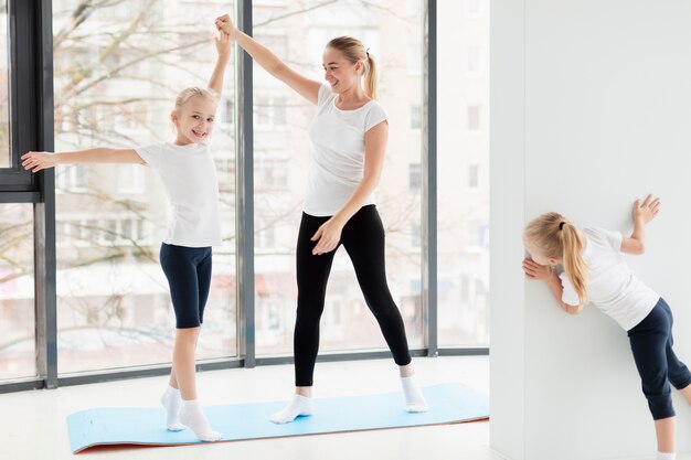 Mère travaillant avec des filles à la maison sur un tapis de yoga