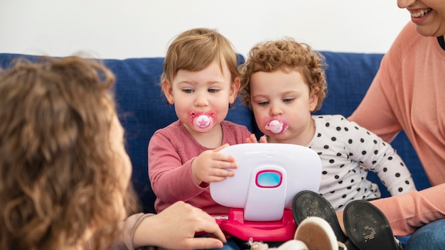 Mères LGBT à la maison sur le canapé jouant avec les enfants