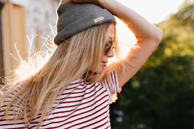 Merveilleuse femme posant en plein air tenant un chapeau gris