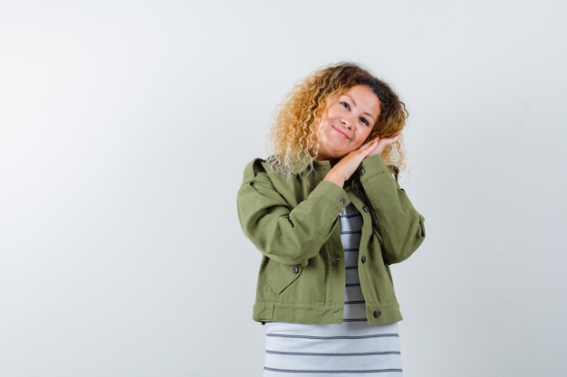 Merveilleuse femme en veste verte, chemise penchée joue sur les mains et à l'optimiste, vue de face.