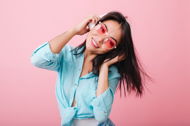 Merveilleuse fille asiatique avec une expression de visage heureux agitant les cheveux tout en écoutant de la musique. Modèle féminin hispanique mignon se détendre avec la chanson préférée.