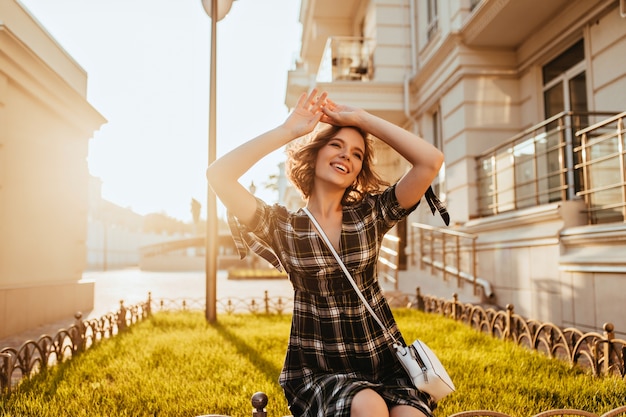 Merveilleuse jeune femme posant en journée d'automne ensoleillée. Rire à la mode dame blanche se détendre en septembre matin.