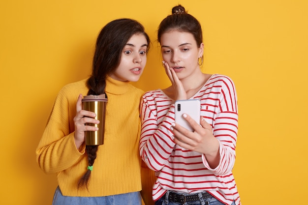 Mesdames avec téléphone intelligent dans les mains et à emporter le café