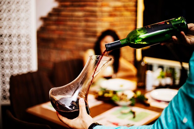 Photo gratuite mettre le vin rouge de la bouteille dans un bocal en verre.