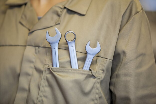 Mi-section de mécanicien femme avec des outils dans la poche