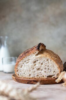 Miche de pain au levain fraîchement cuit sur une planche à découper avec du lait. pain rustique artisanal au levain.