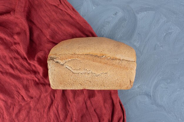 Miche de pain sur une nappe rouge sur table en marbre.