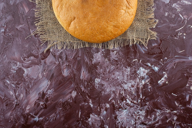 Une miche de pain rond avec une croûte sur un sac.