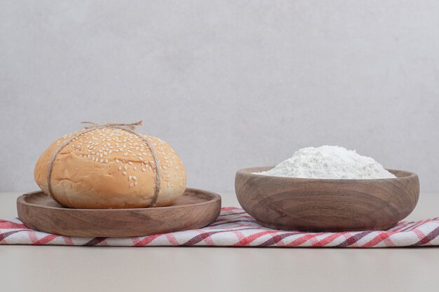 Michez un pain burger en corde avec de la farine sur une plaque en bois. Photo de haute qualité