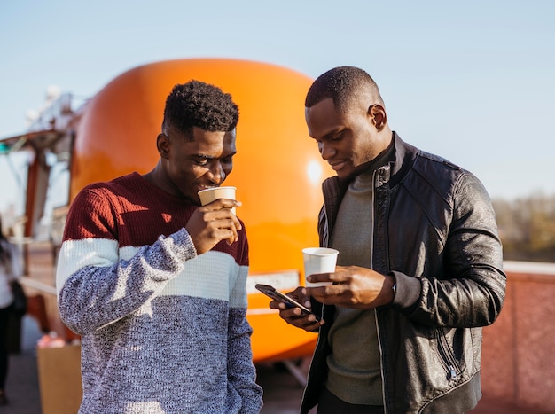 Photo gratuite mid shot amis profitant d'un café devant un camion de nourriture