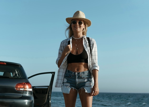 Photo gratuite mid shot femme blonde avec chapeau près de la mer