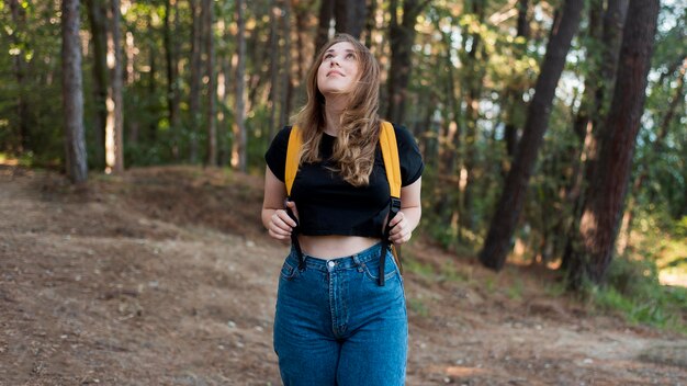 Mid shot femme blonde avec sac à dos dans les bois