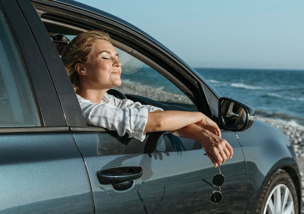 Photo gratuite mid shot femme blonde en voiture regardant la mer