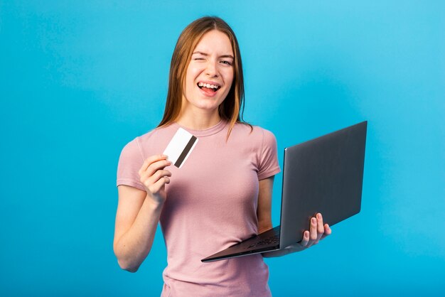 Mid Shot femme tenant une carte de crédit et un ordinateur portable