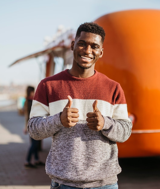 Photo gratuite mid shot homme heureux devant un camion de nourriture