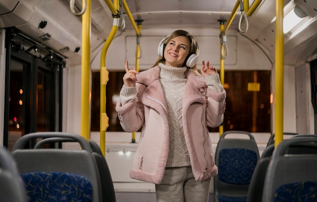 Mid shot smiling woman wearing headphones in bus