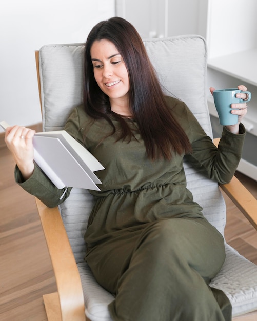 Mid shot woman reading book et boire du café