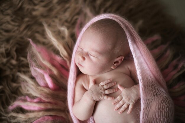 Mignon dormeur nouveau-né fille en rose sur laine