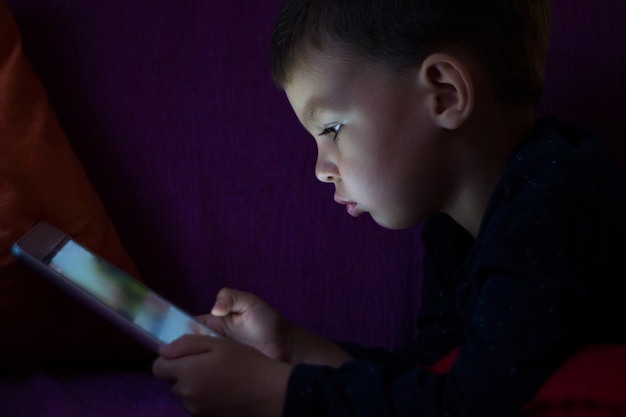 Mignon enfant avec tablette dans l&#39;obscurité