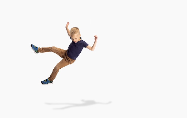 Un mignon garçon d'âge préscolaire isolé sur le mur blanc du studio