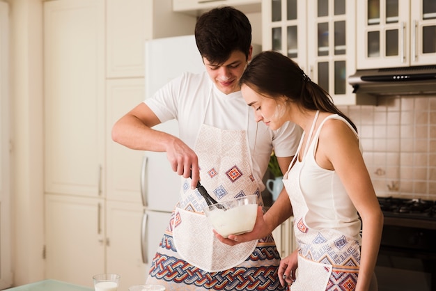 Mignon jeune homme et femme préparant des pâtisseries ensemble