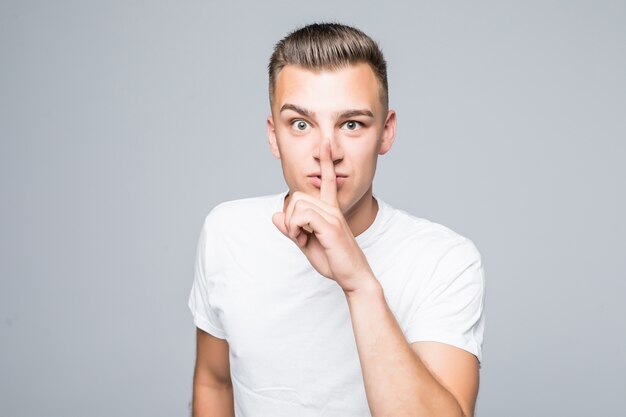 Mignon jeune homme garçon montre être tout à fait signe isolé sur mur blanc