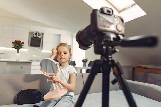 Mignon petit blogueur avec des cosmétiques d'enregistrement vidéo à la maison