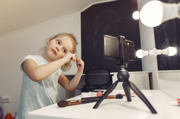 Mignon petit blogueur avec des cosmétiques d'enregistrement vidéo à la maison